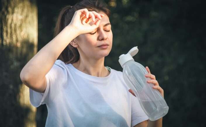 mulher com pressão baixa no calor toma água