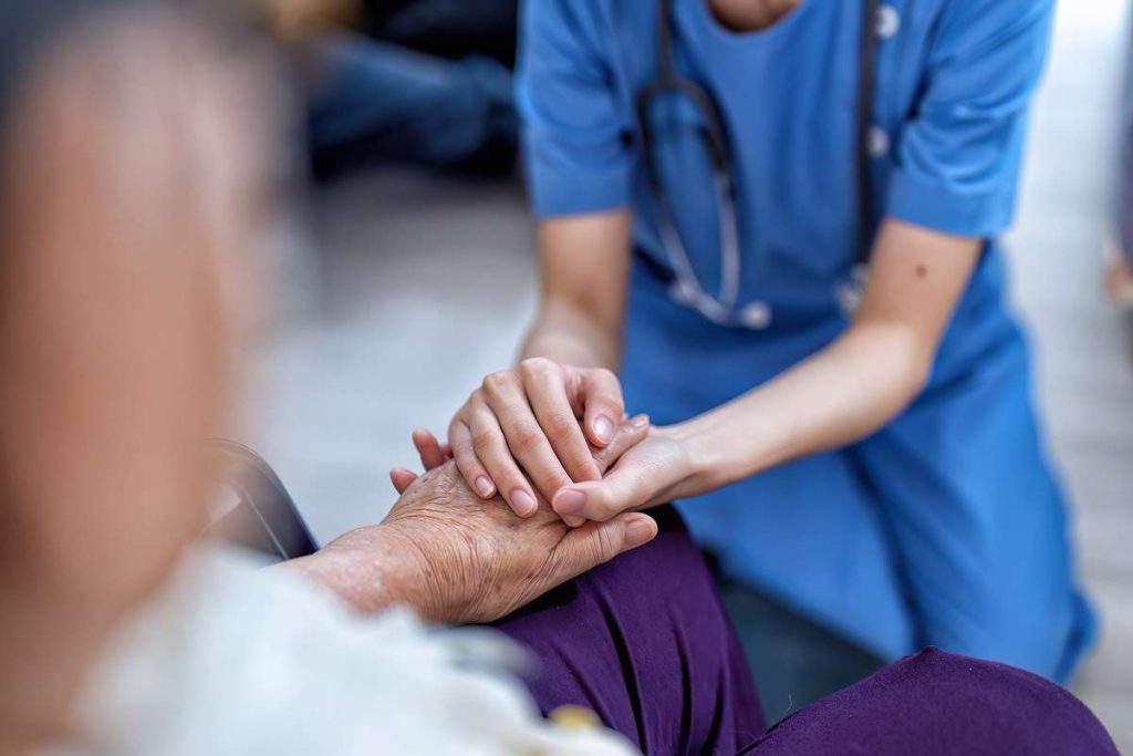 profissional de cuidados paliativos segurando a mão de paciente
