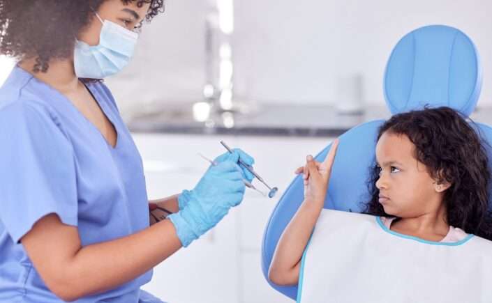 criança com medo de dentista no consultório com profissional