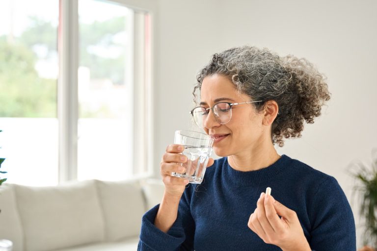 mulher ingerindo comprimido de vitamina B12