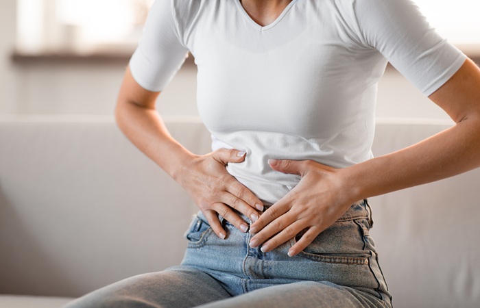 Mulher com mãos na barriga sintomas de constipação intestinal